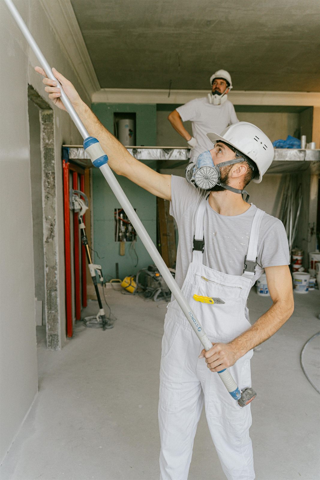 Painters working from a lift in a large interior space