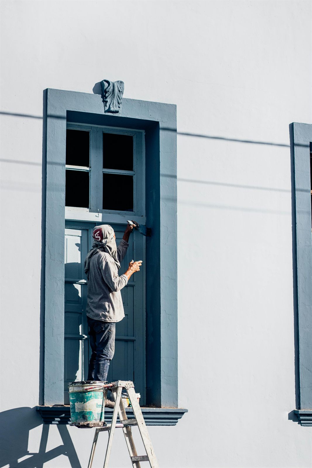 Painter applying blue paint around an exterior window
