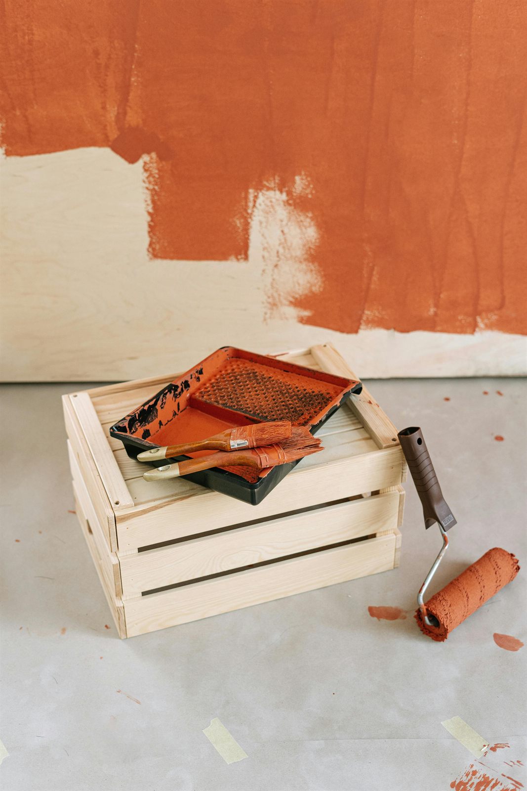 Paint tray and roller beside a freshly painted wall